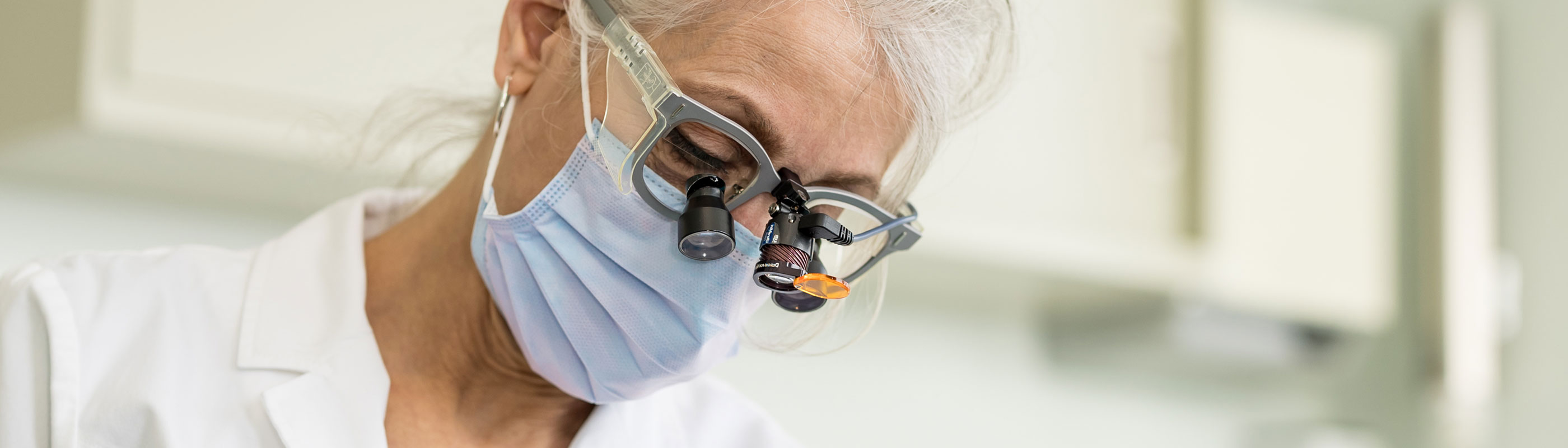 A dentist works with her patient wearing protective glasses.